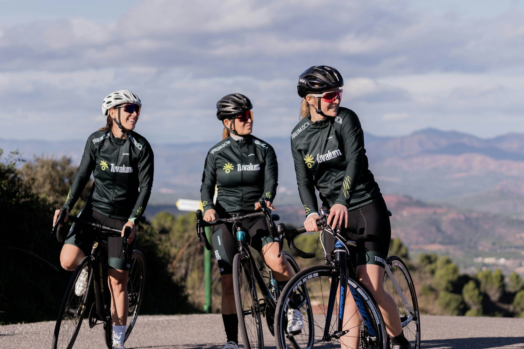 Three cyclists enjoying a stop together with a mountain landscape behind them